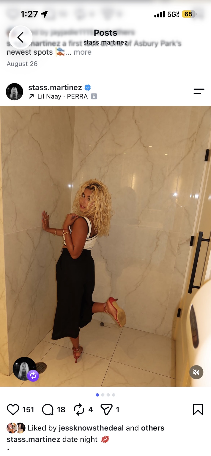 Stass in a black and white outfit against a marble wall